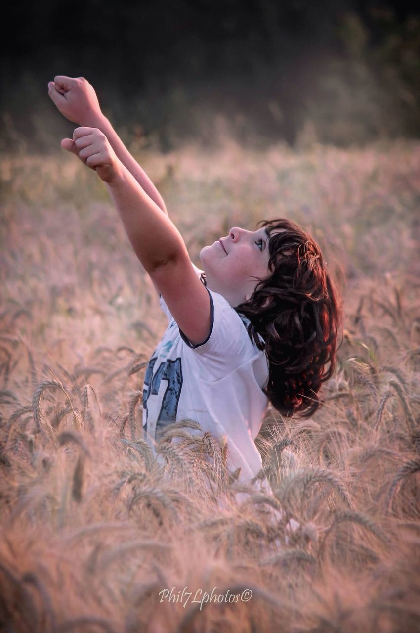 lifestyles, leisure activity, person, focus on foreground, holding, rear view, outdoors, standing, selective focus, casual clothing, field, day, men, sunlight, part of, young women