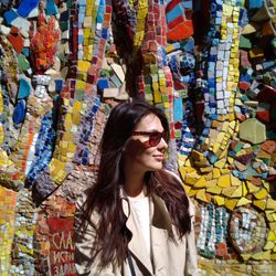 Portrait of smiling young woman wearing sunglasses against mosaic wall