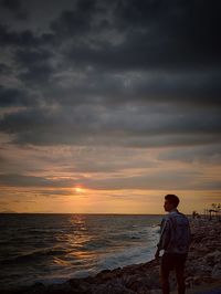 Man standing on beach against sky during sunset