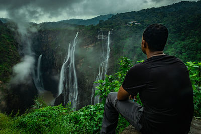 Rear view of man looking at waterfall