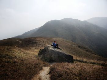 Rear view of man standing on mountain against sky