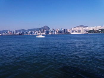 Sea by buildings against clear blue sky