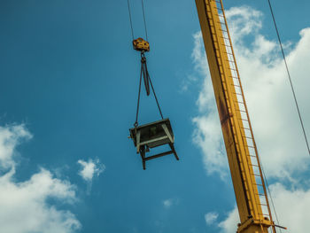 Low angle view of crane at construction site against sky