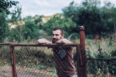 Portrait of young man looking through fence