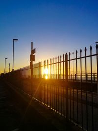 Silhouette fence against clear sky during sunset