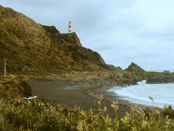 Lighthouse by sea against sky