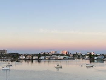 Buildings by sea against sky during sunset