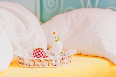Coffee cup and saucer with eggcup in basket on bed