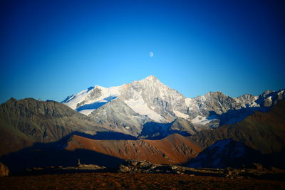 Scenic view of snowcapped mountains against blue sky