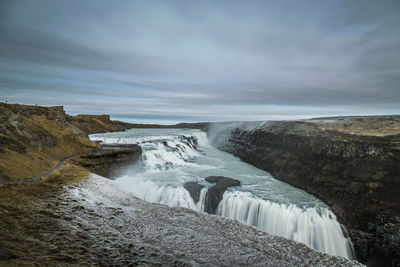 Scenic view of waterfall against sky