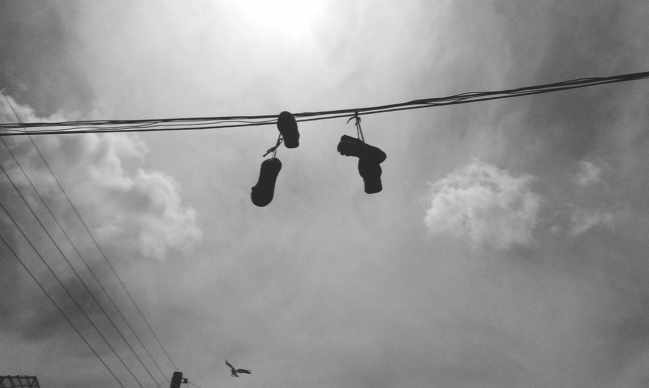 low angle view, sky, cable, silhouette, power line, hanging, bird, lighting equipment, street light, cloud - sky, animal themes, electricity, connection, outdoors, perching, day, flying, power cable, no people, cloud