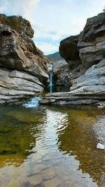 Rock formation in water against sky