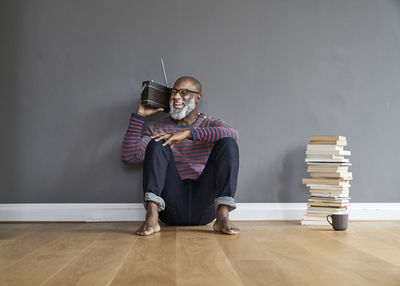 Mature man sitting on floor listening to the radio, laughing