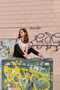 Portrait of young woman standing against wall