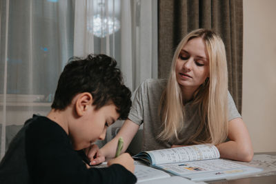 Mom and son are doing homework. sister helps brother solve math. home schooling. high quality photo