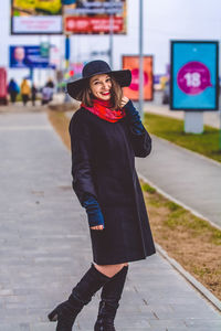 Portrait of smiling woman standing on footpath in city