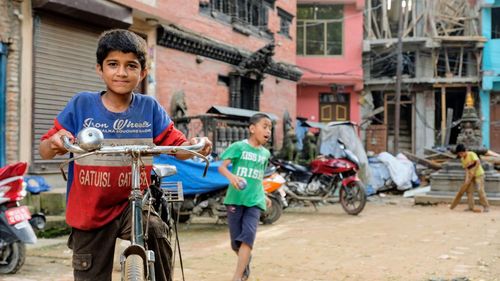 Portrait of boy with bicycle against building in city