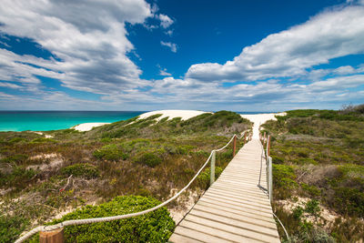 Scenic view of wooden boardwalk leading to sea at de hoop nature reserve south africa against sky