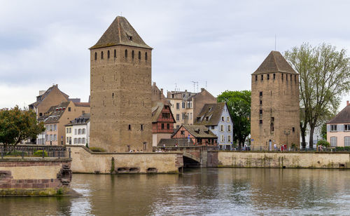 Buildings by river against sky