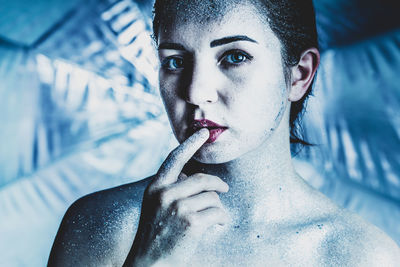 Portrait of young woman with glitters touching lips