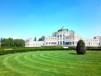 Lawn by building against clear blue sky during sunny day