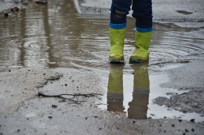 Low section of person wearing boots while standing in puddle