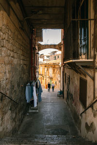 The alley between old ancient buildings with two walking men in palermo.