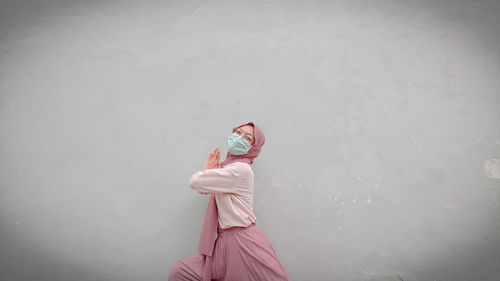 Side view of woman standing against white wall