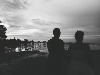 Rear view of silhouette couple standing at beach