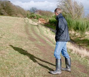 Full length of man with hands in pockets standing on field during sunny day