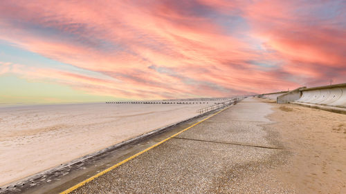 Road amidst land against sky during sunset