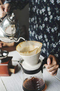 Midsection of woman holding coffee on table