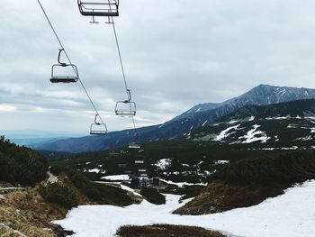 Overhead cable car over snowcapped mountains against sky