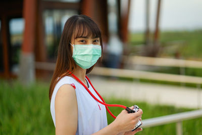 Portrait of woman holding mobile phone outdoors