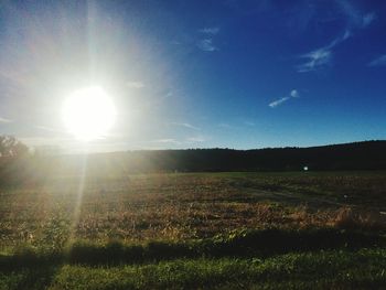 Scenic view of grassy field against bright sun