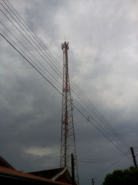 Low angle view of electricity pylon against cloudy sky