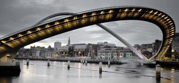 Bridge over river against cloudy sky