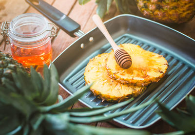 Close-up of honey dipper and pineapple slices in cooking pan