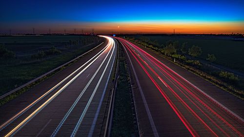 Light trails on road against sky at night