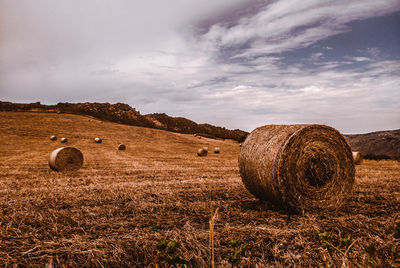 Hay bales on field against sky