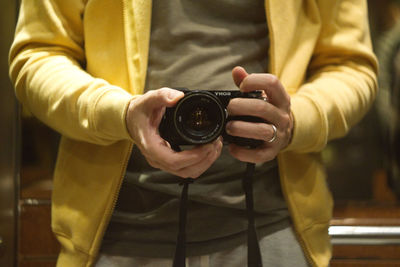 Midsection of man holding camera