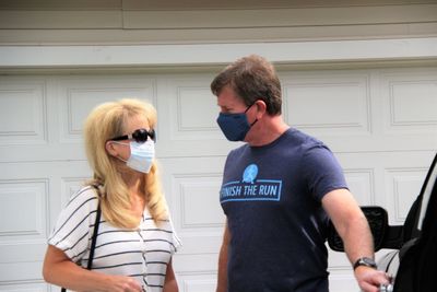 Young couple wear masks  standing against garage door