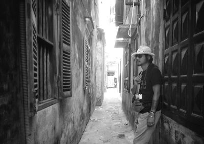 Man standing on alley amidst buildings