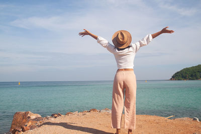 Full length of woman standing at beach against sky