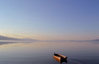 Boat moored in river against clear sky during sunset