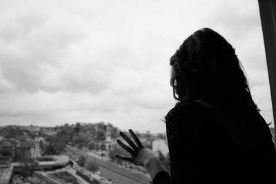 Rear view of woman looking out through apartment window