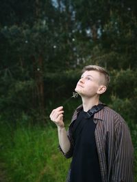 Young man looking away while standing on land