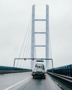 Cars moving on suspension bridge against sky