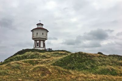 Lighthouse on field against sky