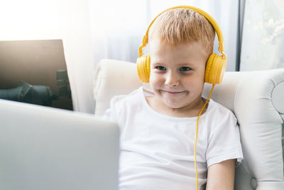 A boy in headphones looks at a laptop screen.